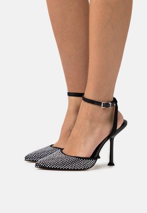 Black high-heeled slingback shoes with pointed toes, adorned with silver rhinestones, featuring an ankle strap and a shiny stiletto heel.