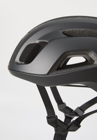 Casque de vélo noir avec une finition lisse, des fentes de ventilation et des sangles ajustables pour un ajustement sécurisé et un confort optimal.