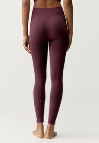 Leggings sportivi bordeaux con texture a coste, vita alta e lunghezza alla caviglia. Dettagli sottili vicino all'orlo migliorano il design.