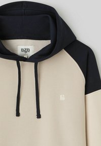 Sweatshirt à capuche beige et marine avec une poche kangourou, des cordons de serrage et un logo discret. Fabriqué en tissu doux en mélange de coton.