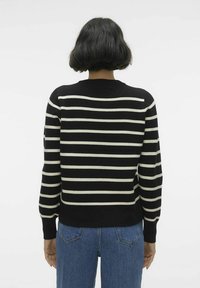 Pull noir et crème à rayures, avec un col rond et des manches longues, fabriqué en matériau tricot doux. Fini texturé, coupe décontractée.