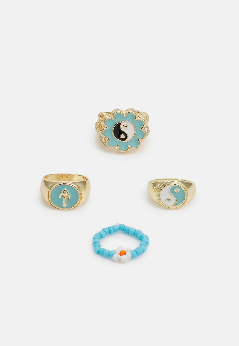 Quatro anéis: metal de tom dourado com detalhes em esmalte turquesa; um apresenta um design yin-yang, outro tem uma seta elevada e um anel com pérolas que possui um motivo de flor.