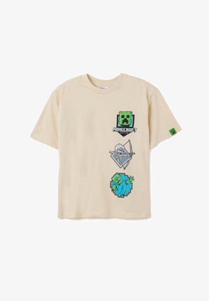 T-shirt en coton beige avec des graphismes Minecraft. Présente un visage de Creeper vert, une forme de diamant et un personnage zombie avec des accents bleus et verts.