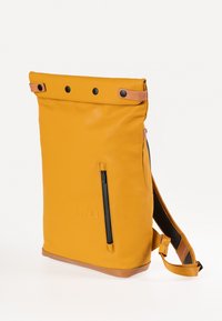 Gelbe Rolltop-Rucksack mit schwarzen Druckknöpfen, seitlicher Reißverschlusstasche, Lederakzenten und verstellbarem Riemen. Glatte Textur und rechteckige Form.