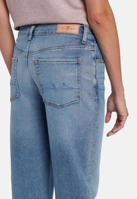 Jeans in denim azzurro chiaro con una vestibilità alta, caratterizzati da tasche posteriori, dettagli di cucitura sottili e una patch in pelle con il logo sulla vita.