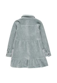 Abito in corda verde chiaro con maniche lunghe, orlo arricciato e polsini con bottoni. Presenta due tasche laterali e un colletto a falda.