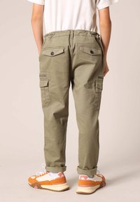Katoenen cargobroek in olijfgroen met een relaxte pasvorm, voorzien van meerdere zakken en een veilige knoopsluiting aan de achterkant. Opgerolde mouwen.