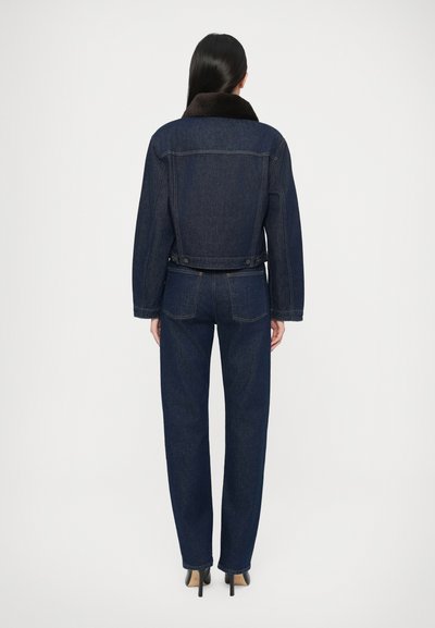 Τζιν μπουφάν με σκουρόχρωμο ντεντέλ, καφέ γούνινο γιακά, άνετη γραμμή και κουμπιά στη μέση. Συνδυάζεται με τζιν παντελόνια στο ίδιο σκοτεινό χρώμα.