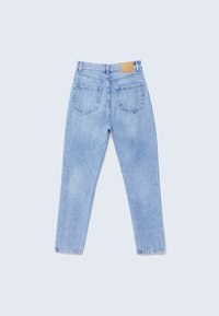 Jeans de mezclilla de tiro alto en azul claro con bolsillos traseros y una etiqueta de marca de cuero marrón en la cinturilla, dispuestos sobre un fondo claro.
