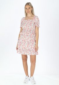 Kleid mit Blumenmuster, gesmoktem Oberteil, quadratischem Ausschnitt und Puffärmeln; es hat rüschendetails und endet oberhalb des Knies.