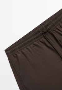 Bruine shorts met een gestructureerde afwerking, voorzien van een elastische tailleband en een verstelbaar trekkoord voor een veilige pasvorm.