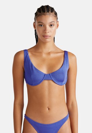 Ein lila metallischer Bikini-Oberteil mit breiten Trägern, einer strukturierten Silhouette und einem geschwungenen Nahtdesign. Glatte Textur und minimale Akzente.