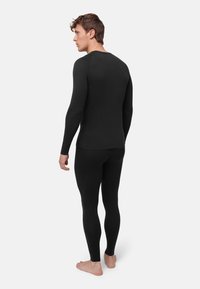 Svart termisk långärmad topp och åtsittande leggings gjorda av slät tyg, designade för komfort och värme, med långa ärmar och rund hals.