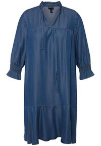 Denimmekko, jossa on rento leikkaus, V-pääntie, pöyhitty kolmannen osan hihansuut ja kerroksellinen helma keskitummassa sinisessä sävyssä.