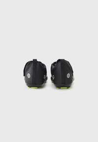 Baskets de sport noires avec un dessus lisse et des accents en mesh, un design bas et des semelles en caoutchouc vert. Détails du logo à l'arrière.