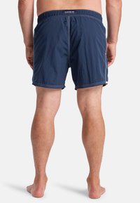 Navy blue swim shorts with an elastic waistband, featuring two rear eyelets and contrasting white stitching. Lightweight, quick-drying fabric.