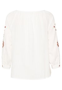 Blouse blanche à manches longues avec broderies florales brunes sur les manches, coupe ample, encolure froncée et poignets à boutons.