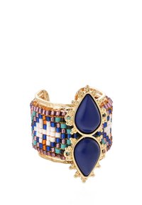 Bracelet en forme de manchette en ton or présentant un design de perles tissées colorées, deux pierres en forme de goutte d'eau bleu marine et des accents en métal complexes.