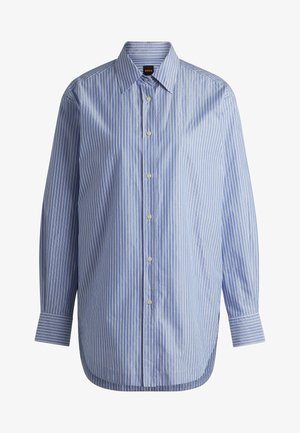 Sininen ja valkoinen raitapaita, jossa on kaulus, pitkät hihat ja pyöristetty helma. Valmistettu sileästä kankaasta, jolla on hienovarainen kiilto.