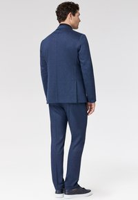 Marineblauw pak met bijpassende broek van gestructureerde stof, met een getailleerde pasvorm, enkele split en strak, minimalistisch ontwerp zonder zichtbare patronen.