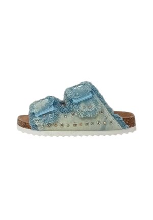 Sandale à glissière en denim bleu avec des bords effilochés, deux straps ajustables, des clous décoratifs et une semelle intérieure en liège texturé, dotée d'une semelle en caoutchouc blanche.