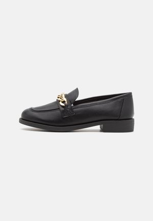 Black leather loafer with low heel and gold chain detail across the top, shown in side profile on a white background.
