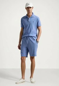 Jasnoniebieska koszulka polo z kołnierzykiem, w komplecie z dopasowanymi szortami. Biała czapka i trampki. Casualowy, miękki w dotyku materiał bawełniany.