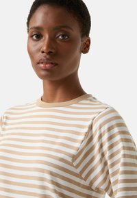 Beige and white striped t-shirt made of soft fabric. Features a round neckline and short sleeves. Classic fit with a relaxed silhouette.