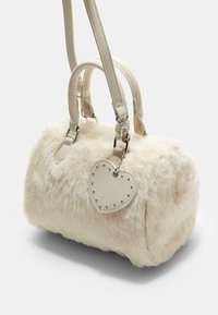 Borsa in pelliccia sintetica color crema, di forma rotonda con due manici superiori e una tracolla removibile. Presenta un ciondolo a forma di cuore con borchie attaccato.