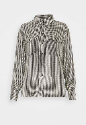 Chemise à carreaux pied-de-poule noir et blanc, boutonnée, manches longues, col et deux poches poitrine à rabat avec boutons.