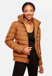 Giacca puffa marrone con cappuccio, caratterizzata da una texture trapuntata, apertura frontale con zip e polsini elasticizzati. Due tasche laterali con dettagli in metallo nero.