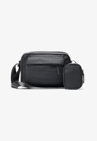 Borsa a tracolla nera realizzata in materiale liscio, con una tasca frontale con zip e una piccola pochette staccabile con chiusura a zip. Spallaccio morbido.