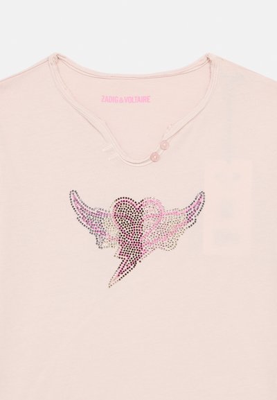 Ροζ βαμβακερή μπλούζα με διακοσμητικό σχέδιο από κρύσταλλα που απεικονίζει φτερά και μια καρδιά με κεραυνό. Λεπτομέρεια με δύο κουμπιά στο λαιμό.
