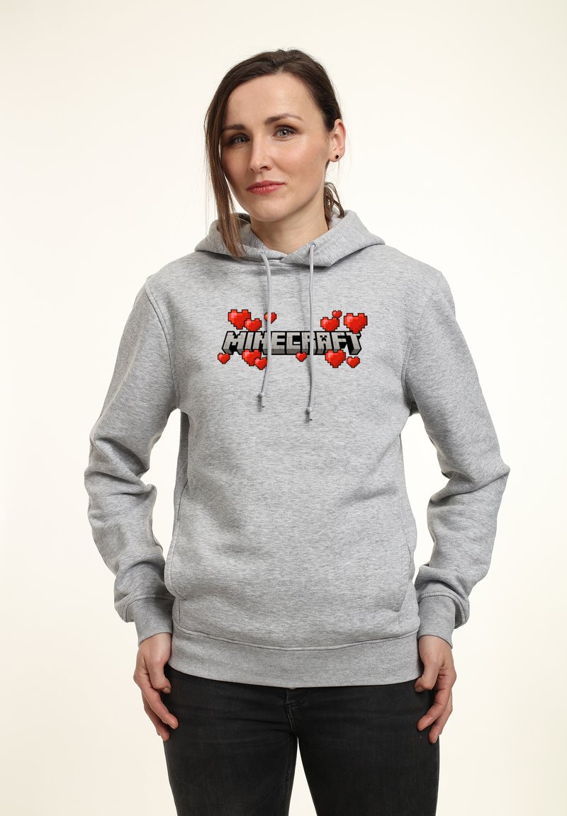 Szara bluza z kapturem z grafiką na przodzie przedstawiającą słowo "Minecraft" na czarnym tle, otoczone pixelowymi czerwonymi sercami. Sznurki na szyi.