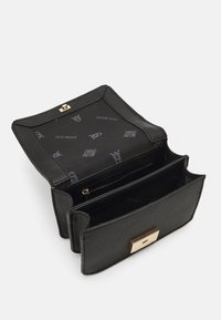 Svart strukturerad läderhandväska med ett guldspänne. Inuti finns flera fack och en fodring med logotypmönster. Öppen design för synlighet.