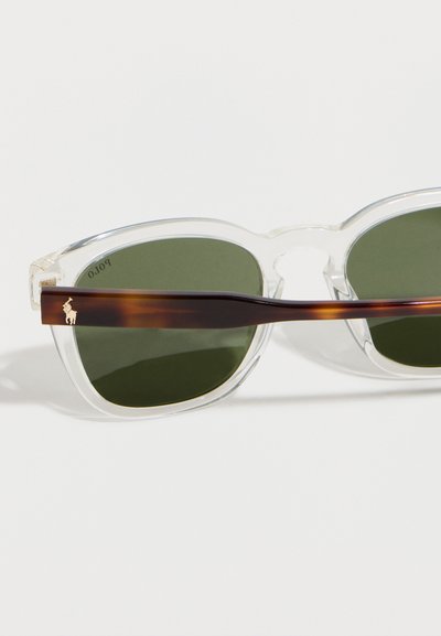 Γυαλιά ηλίου με καθαρό σκελετό, πράσινους φακούς και μπράτσα σε σχέδιο χελωνόκερου με μικρό χρυσό λογότυπο Polo στη αριστερή πλευρά.