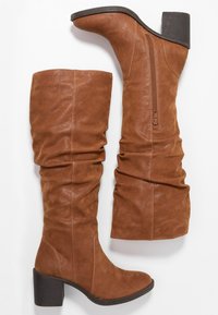Brown suede knee-high boots with a slouchy design, curved toe, and block heel. Features a side zipper for easy wear.