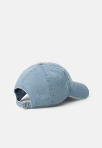 Lys blå denimcaps med buet skygge, justerbar bakre stropp og ventilasjonsåpninger. Lett tekstur med en uformell design.