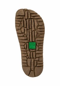 Suela de goma marrón con un patrón de textura y relieve. Presenta un emblema de rana verde en un cuadrado cerca del centro.