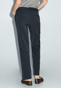 Grijze broek met een getailleerde pasvorm, voorzien van een gladde textuur, rechte pijpen en twee achterzakken. De kleur is donker antraciet.