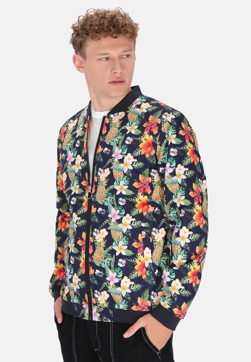Giacca bomber floreale con base blu navy, motivi tropicali colorati, polsini a costine e zip sul davanti. Realizzata in tessuto leggero.