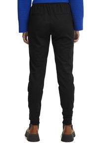 Črne športne hlače s prilegajočim dizajnom, elastičnim pasom in dvema zadnjima žepoma. Material se zdi gladek z rahlim sijajem.