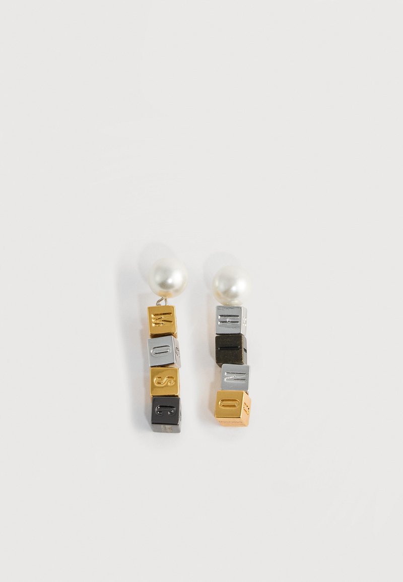 Boucles d'oreilles clou en perle avec des cubes suspendus en or, argent et lettres noires formant le mot "MOSCHINO".
