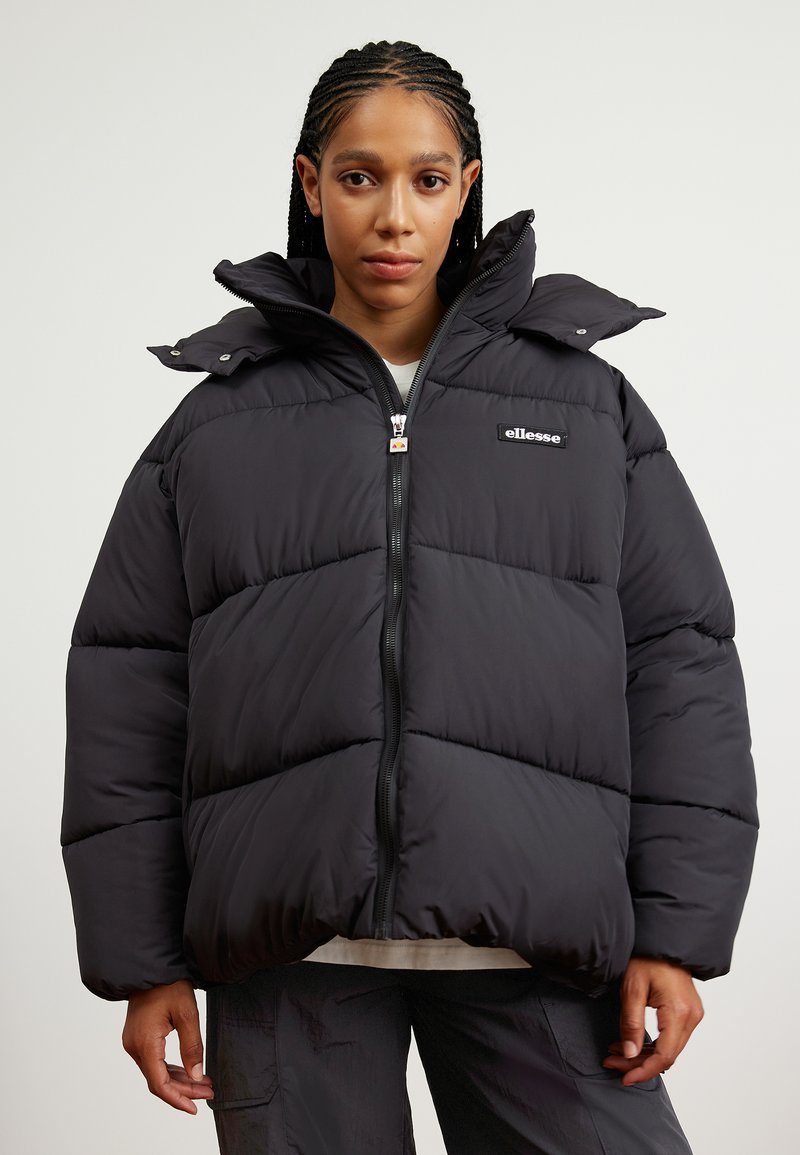 Čierna puffa bunda s vysokým golierom, zipsom vpredu a elastickými manžetami. Obsahuje prešité časti a nášivku s logom na hrudi.