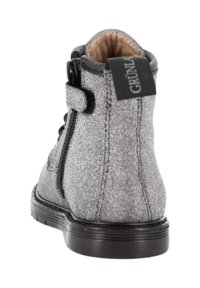 Stivaletto alla caviglia in tessuto grigio con una trama liscia, chiusura laterale con zip e suola in gomma nera a contrasto. Presenta un'etichetta con logo nero sul retro.