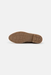 Semelle de chaussure marron avec un motif de texture pour une meilleure adhérence, bout arrondi et finition lisse. Étiquette de taille "37" visible sur le côté.