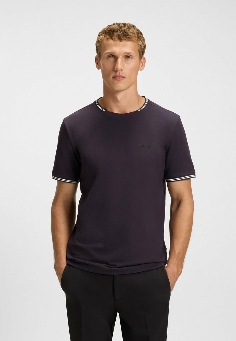Dark purple short-sleeve t-shirt with contrasting white-striped collar and cuffs. Features a subtle logo on the chest. Smooth fabric texture.