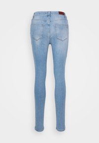 Jeans ajustados en denim azul claro. Presentan una cintura alta con un parche de cuero con marca, cinco bolsillos y una textura lisa, ligeramente deslavada.