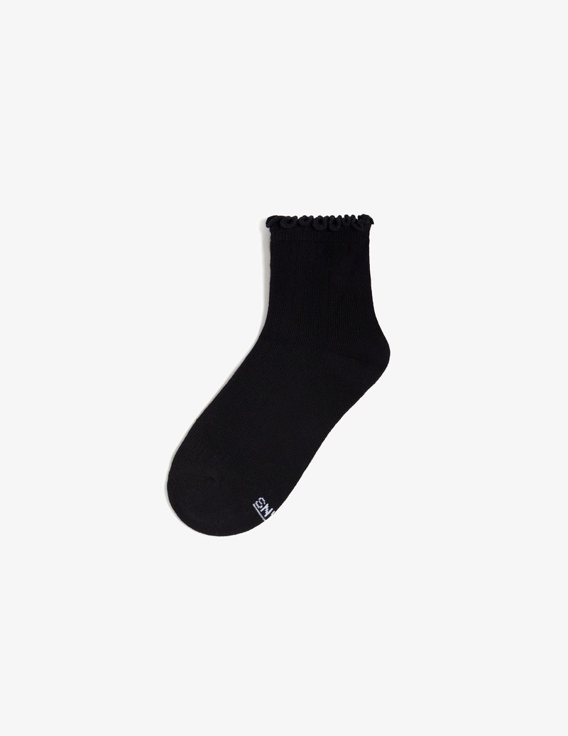 Schwarze Knöchel-Socke mit einem fransigen Saum, aus einem glatten, dehnbaren Material. Verfügt über eine verstärkte Zehenpartie und ein kleines weißes Logo auf der Sohle.