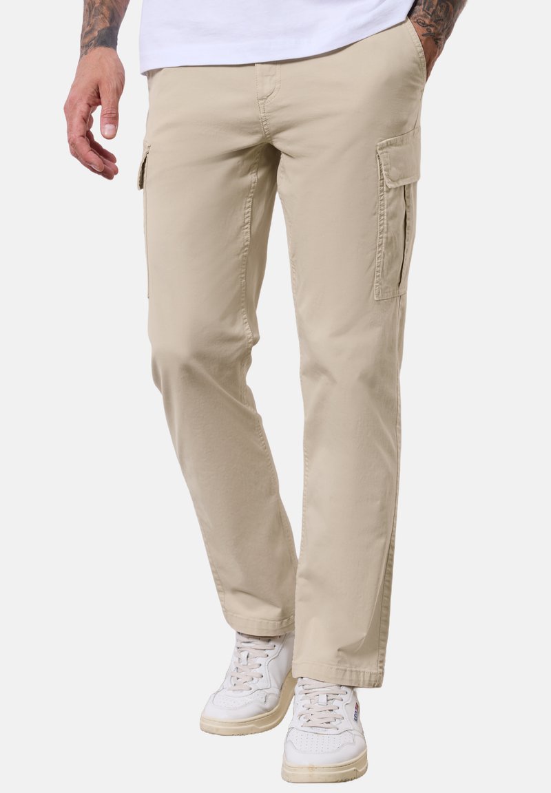 Béžové cargo kalhoty z bavlny, s bočními kapsami a rovnými nohavicemi, doplněné bílými teniskami.
